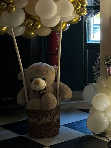 A teddy bear in a wicker basket, designed to look like a hot air balloon. This is a charming and creative decor element that guests always love.