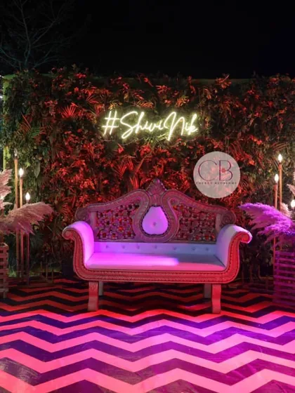 We set the stage for a memorable Sangeet night with this stunning photo booth. The design combines a lush green wall, pampas grass arrangements, and a custom neon hashtag, all set against a vibrant chevron-patterned dance floor.