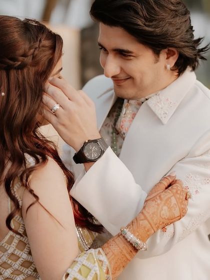 A tender moment between the couple, with the bride's henna-stained hands gently held by the groom.