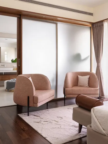 The primary room in 'A Walk in the Clouds' features a custom Californian-sized upholstered bed and a sitting area with pink armchairs.