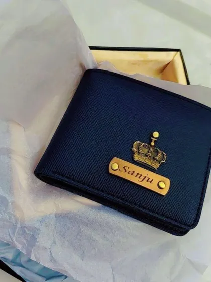 A beautifully shot image of a personalized navy blue wallet with a crown charm, nestled in its gift box with soft tissue paper.