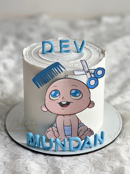 A clean and simple Mundan ceremony cake. This design features a cute, hand-painted baby illustration with a fondant comb and scissors.