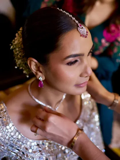 Getting ready for her beachside wedding. The sleek bun is a practical and chic choice for a destination wedding, keeping her cool and elegant.