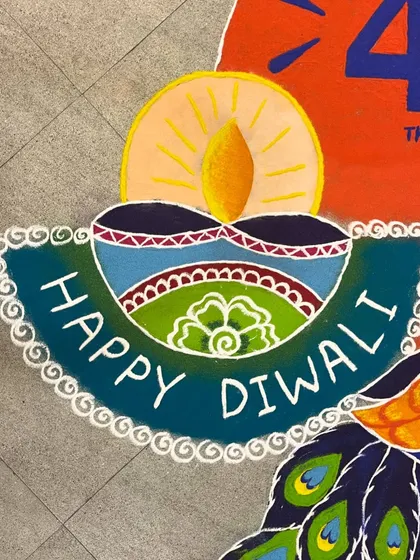 Detail shot of the "Happy Diwali" message and diya from a branded floor art piece. Even with custom text and logos, I ensure the traditional festive feeling is central to the design.