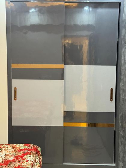 A modern sliding wardrobe in grey and white, accented with a gold-colored band for a touch of luxury.