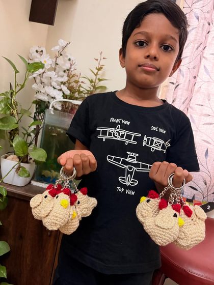 My son proudly showing off a bulk order of crochet chicken keychains. It's always a family affair here at Yarn to Masterpiece.