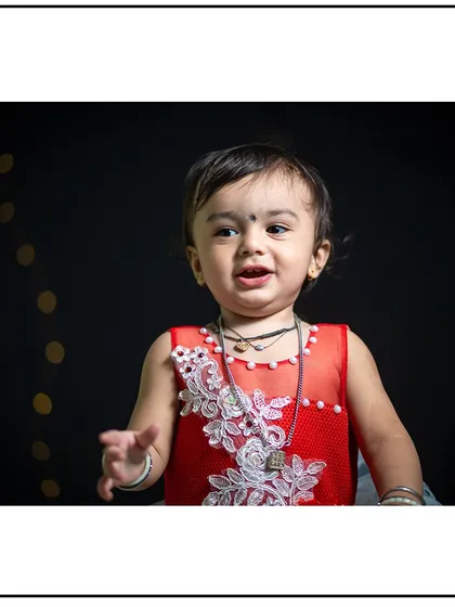 A bright smile from a little girl in a beautiful red dress during her studio photoshoot.