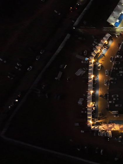 A different angle of the venue at night, highlighting the long rows of vendor stalls and the sheer size of the event grounds.