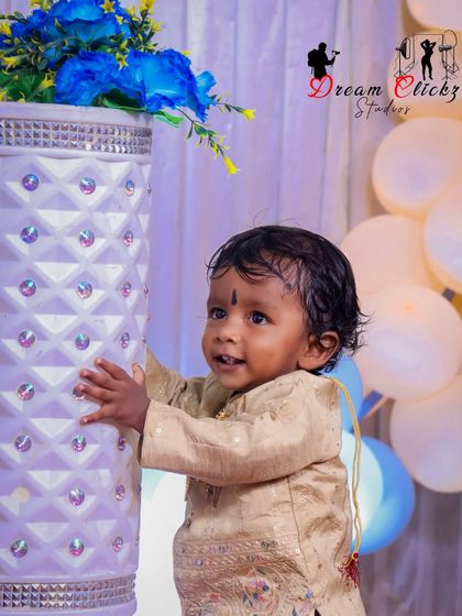 A candid shot of the birthday boy interacting with the party decorations. His happy expression shows how much fun he's having during his special photoshoot.