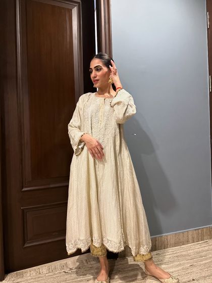 A side view of the off-white Anarkali, highlighting the delicate embroidery and the simple, graceful hairstyle.