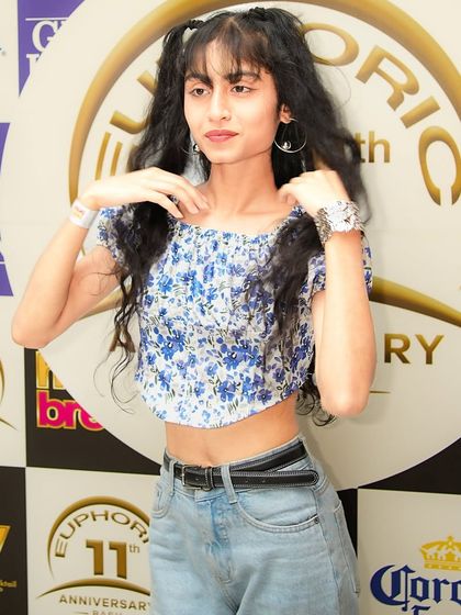 A partygoer posing at the photo-op wall during the club's anniversary. My events attract a fashionable and fun-loving crowd.