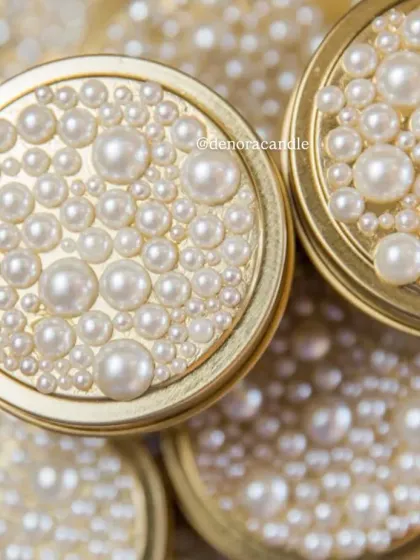 A touch of glamour for your home. This golden tin jar candle is topped with a lid adorned with a cascade of pearls, making it a beautiful decorative object even when not lit.