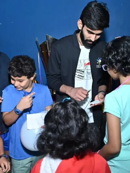 Srikanth Kidambi surrounded by young players, signing autographs. These moments of inspiration are a key part of the events we manage.