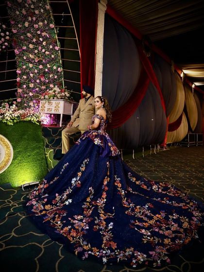 Another angle of a client's grand reception look. Her navy floral ball gown spreads out around her, showcasing the intricate embroidery that covers the entire length of the dramatic train.