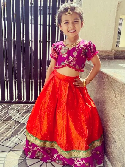 This adorable client is shining in her custom-designed kids' lehenga. I paired a bright orange brocade skirt with a hand-embroidered magenta blouse, creating a comfortable yet festive outfit for a little one.