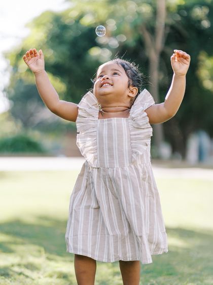 A little girl reaching for a bubble. The wonder and excitement in her eyes are perfectly captured.
