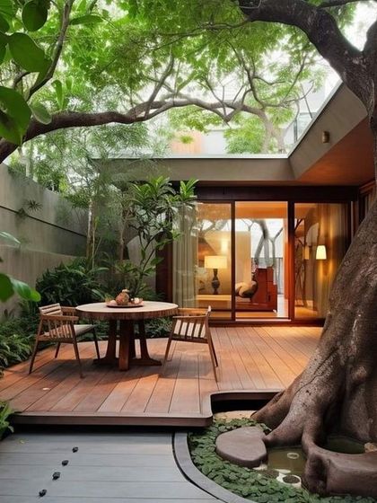 This design creates a stunning indoor-outdoor courtyard feel. A large, mature tree is the centerpiece, with a wooden deck built around it for seating, seamlessly blending the home with the natural environment.