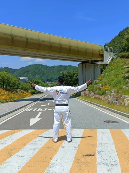 Arms outstretched, embracing the experience of being at the center of the Taekwondo world.