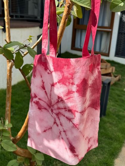 Another view of the beautiful, naturally dyed tote bag hanging on a guava tree. It's a perfect example of a functional, sustainable, and artistic product.