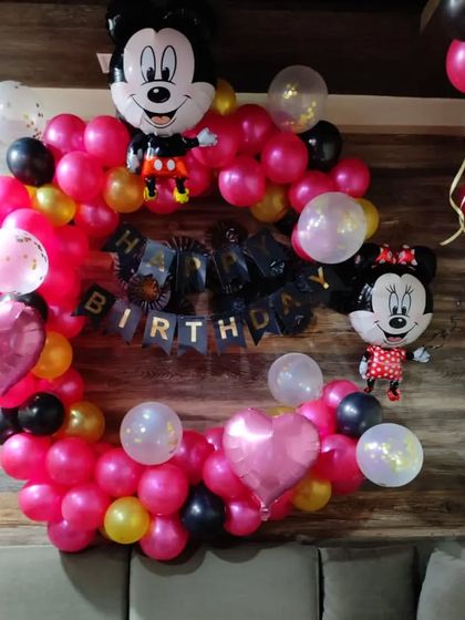 A Mickey and Minnie Mouse themed balloon ring. This home decoration uses pink, black, and gold balloons with character foils to create a fun photo spot.