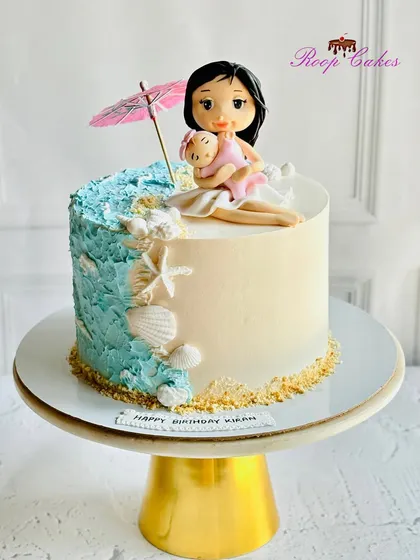 A custom cake for a mom, featuring a beautiful beach theme with a fondant figurine of a mother and child relaxing by the sea.