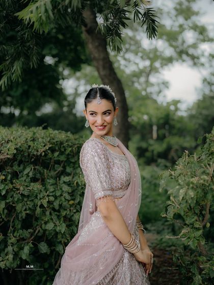 A lovely candid shot of the bride looking over her shoulder with a smile, surrounded by lush greenery.