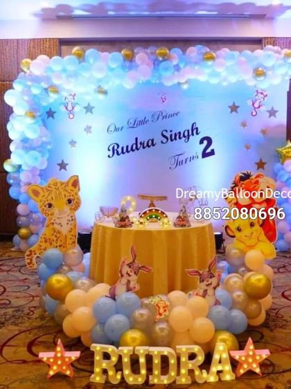 A grand jungle-themed birthday celebration for a little prince. This banquet hall setup features a large backdrop, character cutouts from The Lion King, and custom light-up letters with the child's name.