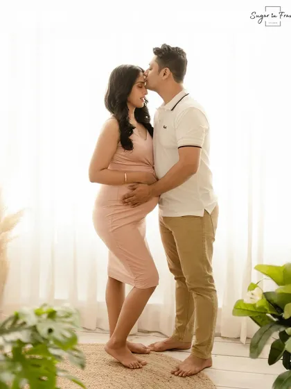 A sweet and simple maternity portrait. The husband kisses his wife's forehead as they stand in soft, natural light, creating a timeless and romantic image.