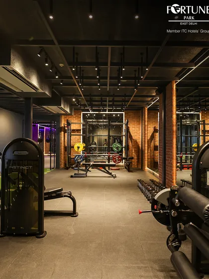 The strength training area is equipped with a variety of machines and free weights to suit a full-body workout. The exposed brick and modern lighting create a motivating, urban gym atmosphere.