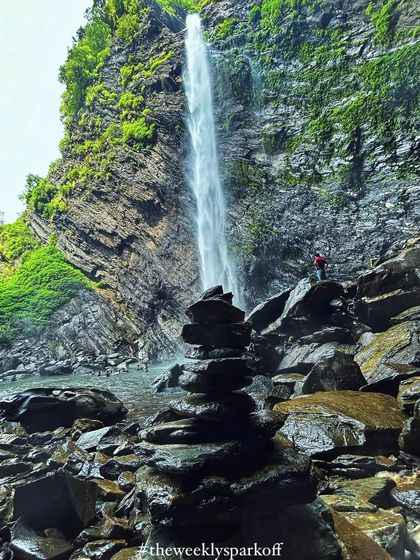 Another perspective of Koodluthirtha Falls, with a trekker standing on the rocks, showing the scale of this magnificent waterfall.