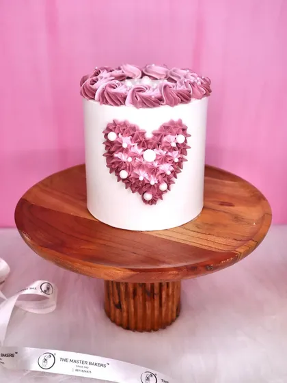 Another view of our lovely heart-themed cake, showcasing the detailed piping work on a wooden cake stand.