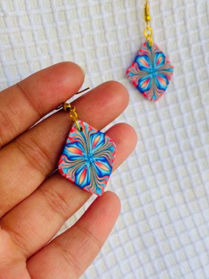 A simple yet stunning diamond-shaped polymer clay earring. The intricate floral cane pattern is created by layering different colors of clay.