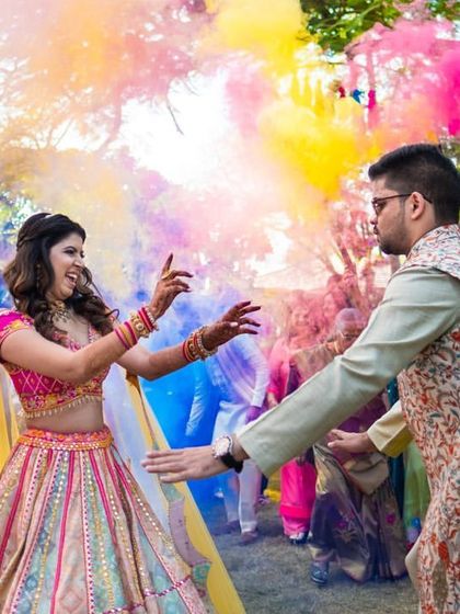 A vibrant shot of the couple dancing amidst colorful smoke bombs during their holi-themed mehendi party.