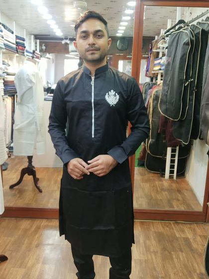This client is seen during a fitting for his black custom kurta. The design features a modern zip placket and a subtle, elegant crest embroidery, demonstrating how we tailor even simple designs to your unique style.