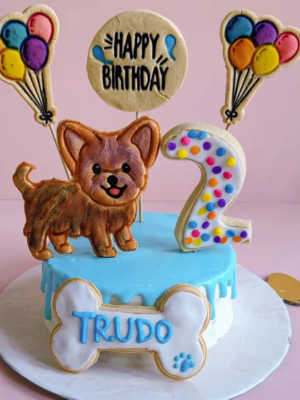 A custom cake for Trudo the Yorkie, with a blue drip and a cookie topper that captures his adorable, alert expression.