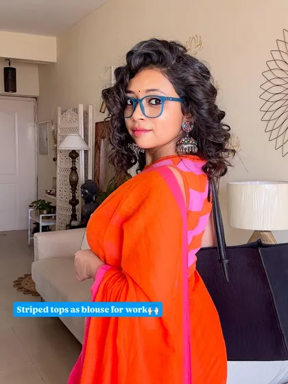 For a chic workwear look, try pairing your saree with a striped top. This orange and pink striped top adds a professional yet stylish touch to a simple linen saree.