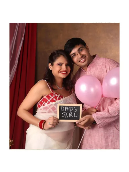 A fun gender reveal shot! This couple announces "Dad's Girl" with a chalkboard sign and pink balloons.