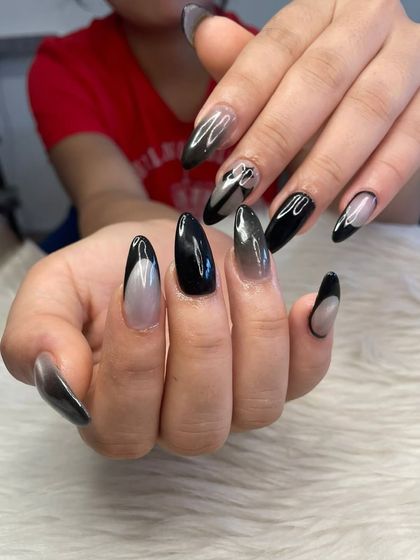 A spooky season design featuring a mix of solid black, black ombré, and abstract black French tips on almond-shaped nails.