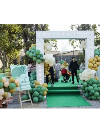 An outdoor entrance arch for a baby shower, decorated with sage green and neutral balloons to welcome guests to the celebration.