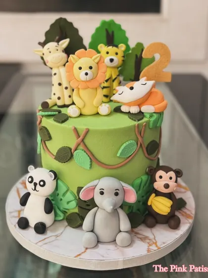 A vibrant green jungle cake surrounded by adorable fondant animals. This design features a panda, elephant, monkey, and more, creating a full safari scene.