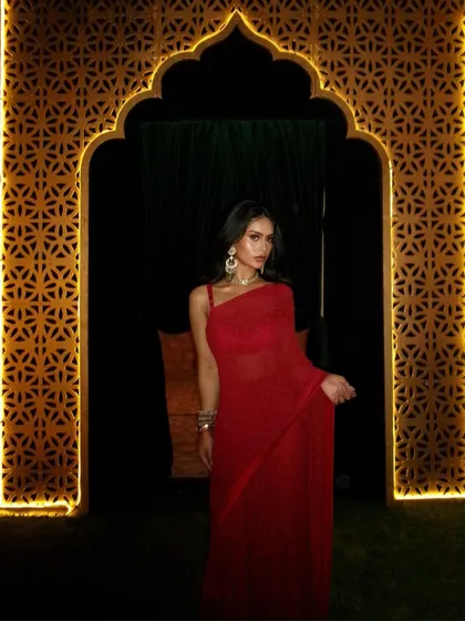 A dramatic shot of Nysa framed by a beautifully lit archway, making the red of the saree stand out against the night.