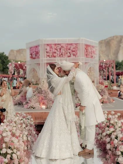 A beautiful moment of the couple against the backdrop of the pink floral mandap I designed. The decor serves as the perfect frame for their love story.