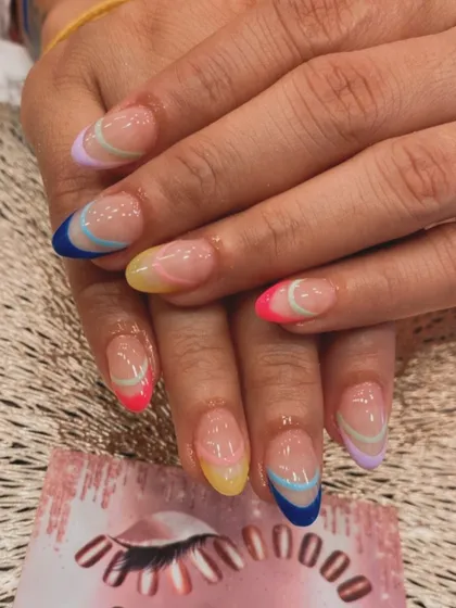 A fun and colorful take on the French manicure. Each almond-shaped nail features a different pastel or bright color at the tip, with delicate curved lines for a modern touch.