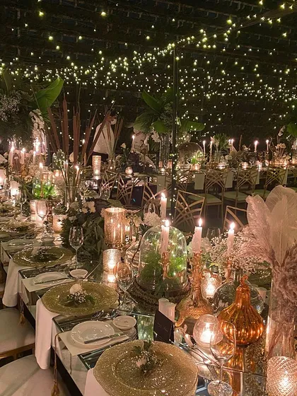 There is magic in the details. I designed this whimsical dining experience under a canopy of countless fairy lights, creating the illusion of a starry night sky. The warm glow of hundreds of candles on mirrored tables adds to the enchanting, intimate atmosphere for a truly memorable reception.