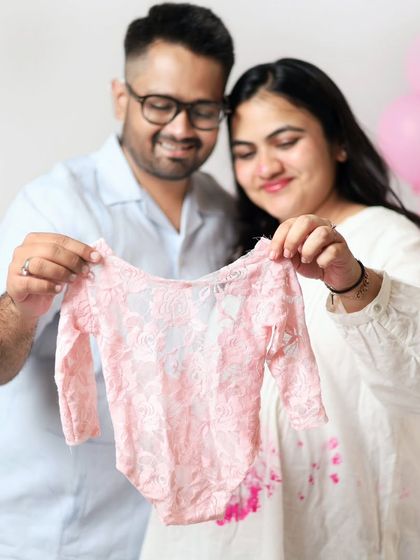 The happy couple holds up a delicate pink onesie, announcing they are expecting a daughter. Their joyful expressions say it all.