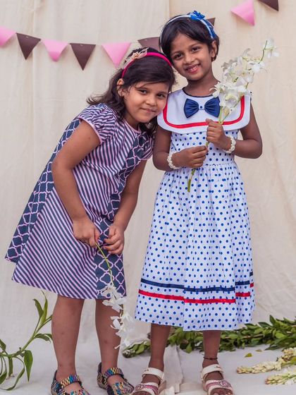 Two friends, two unique styles. One wears a classic polka dot sailor dress, while the other is in a modern mixed-print A-line, showcasing the variety of styles I offer.