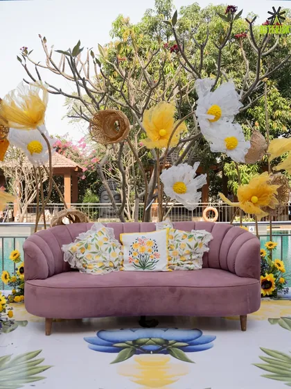 A beautiful mauve sofa with floral cushions, set against a backdrop of paper flowers, creating a perfect photo spot.