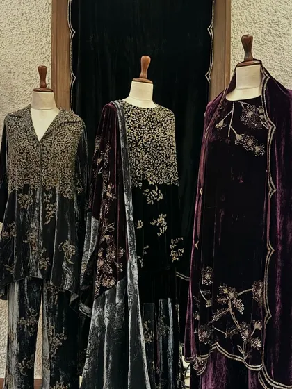 A display of luxurious velvet outfits by Peachoo, in shades of charcoal and deep purple, featuring dense, shimmering embroidery.