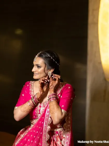 A classic "getting ready" shot. The bride adjusts her earring, giving a great view of her braided hairstyle and glowing makeup.
