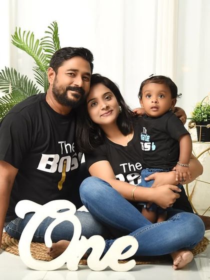 A family celebrating their child's first birthday with matching "The Boss" and "The Real Boss" t-shirts. This fun concept, complete with a "One" prop, adds personality to the milestone shoot.